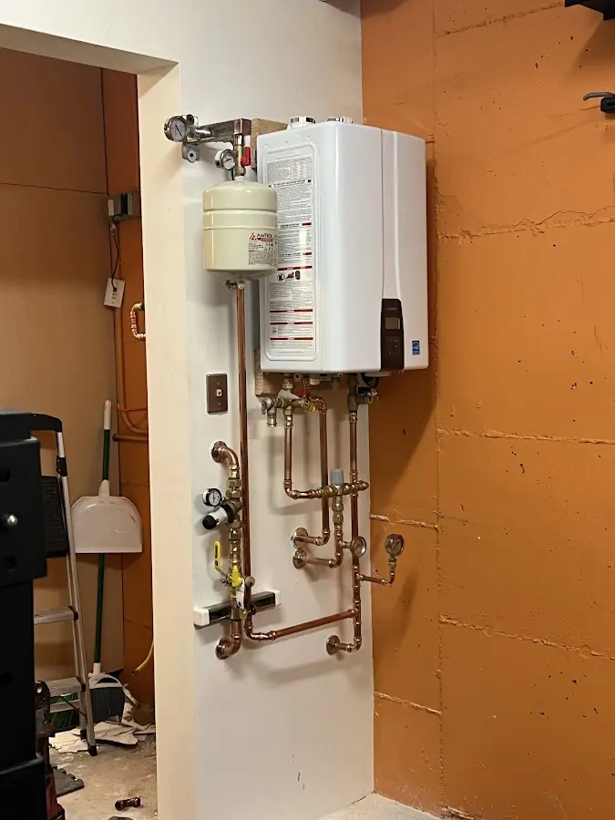 Plumbing technician inspecting water heater connections in Waseca